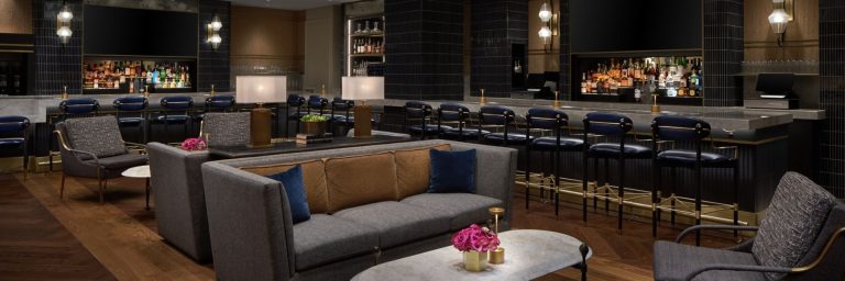 Modern lounge area with tan leather sofa, navy accents, and pink floral centerpiece on marble table