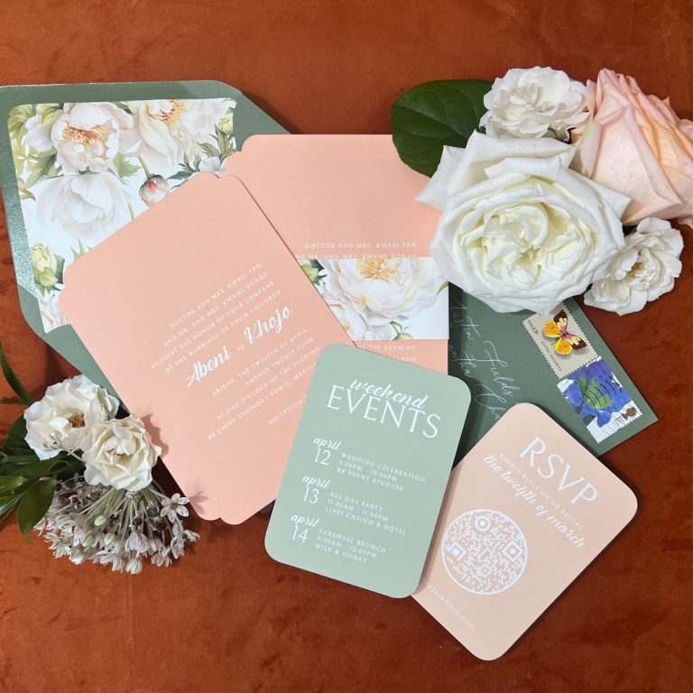 Elegant wedding paper goods in soft peach and green tones styled with white garden roses