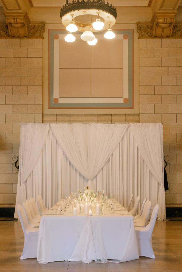 Elegant wedding reception table with white linens, candles, and floral centerpiece under chandelier in historic Nebraska venue