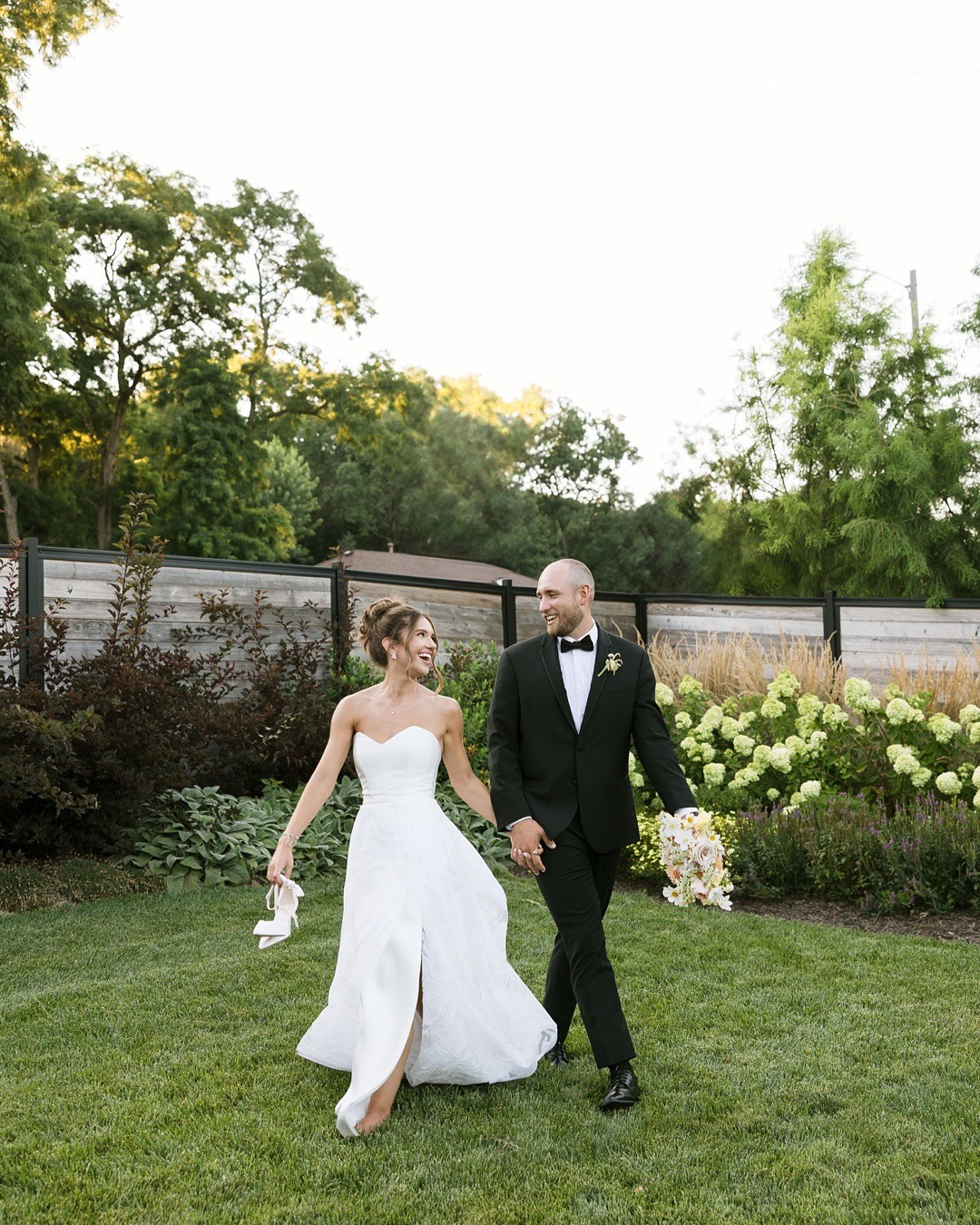 Bride and groom walking together in garden setting at outdoor wedding reception