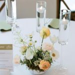Elegant wedding table centerpiece featuring pastel florals with moss base and tall floating candles