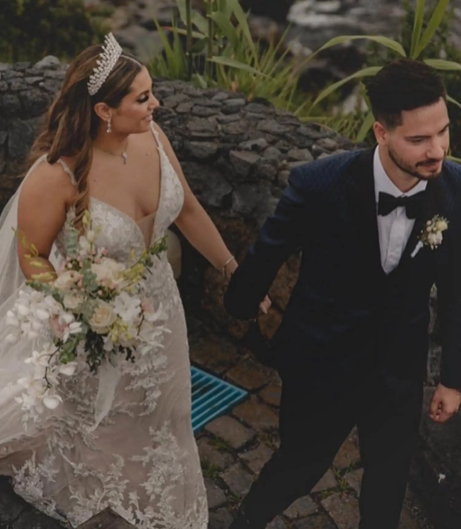 Bride and groom walking together on stone pathway outdoors