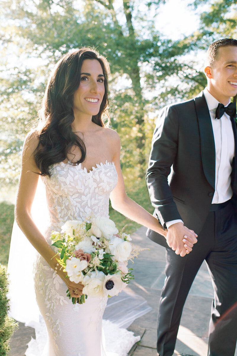 Bride and groom holding hands outdoors in sunny Northern Virginia garden setting