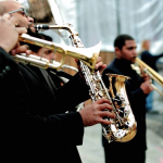 Musicians in black formal attire playing saxophone and brass instruments at wedding ceremony