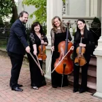 String quartet in formal black attire posing with violins and cello outdoors