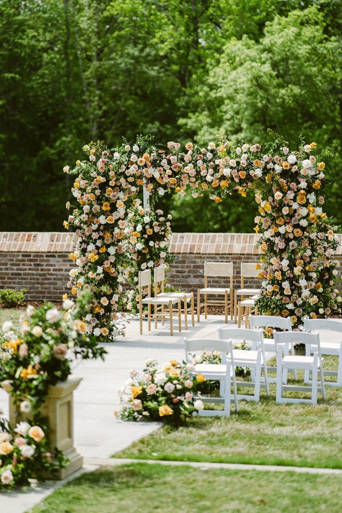 Lush floral arch ceremony backdrop with neutral-toned roses and greenery