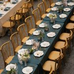 Long banquet tables with teal linens, natural wood chairs, white place settings and gold flatware at The Joslyn