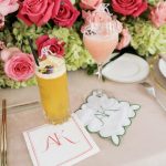 Custom monogrammed napkins and coasters displayed with fresh pink roses and cocktails