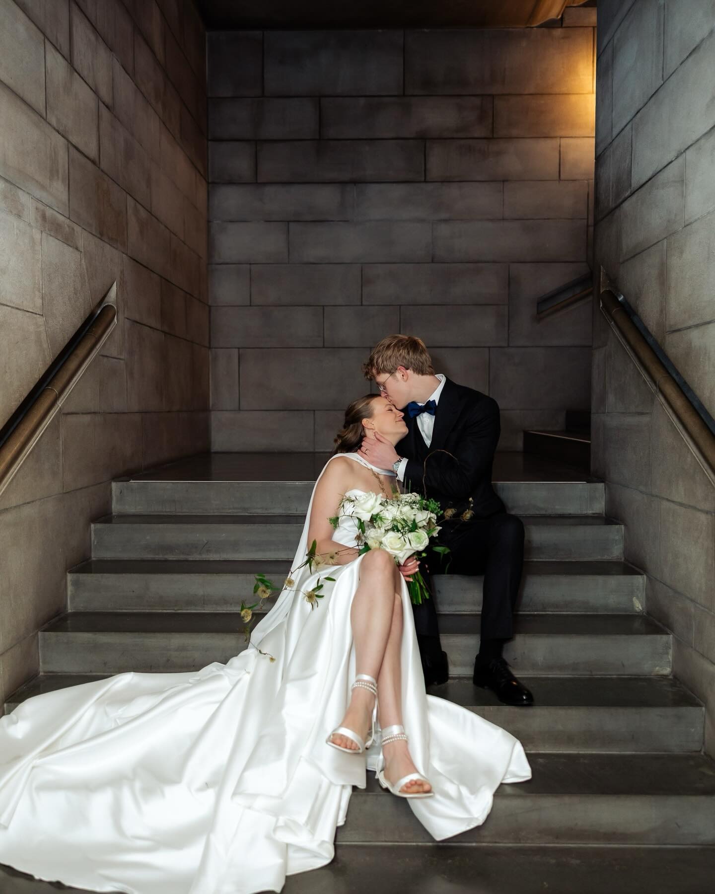Bride and groom kissing on staircase in modern architectural setting