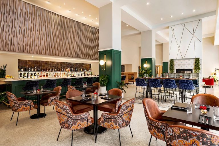 Magnolia Omaha hotel lobby bar with illuminated shelving, velvet seating, and high-top tables