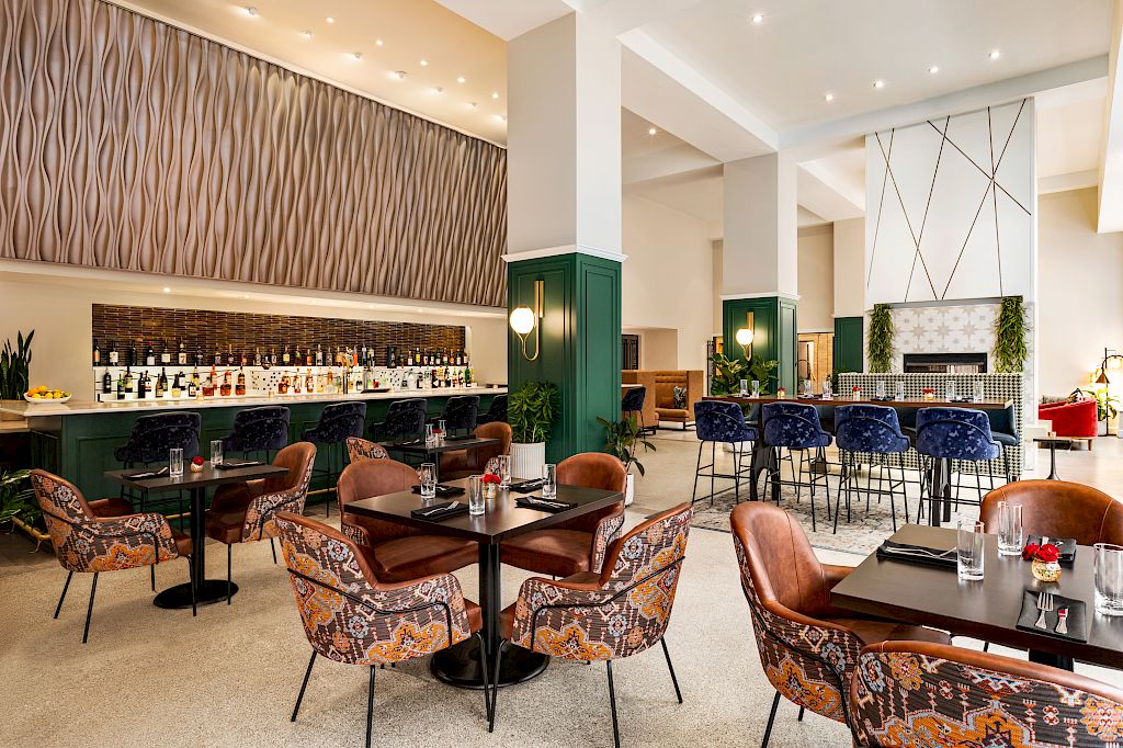 Magnolia Omaha hotel lobby bar with illuminated shelving, velvet seating, and high-top tables