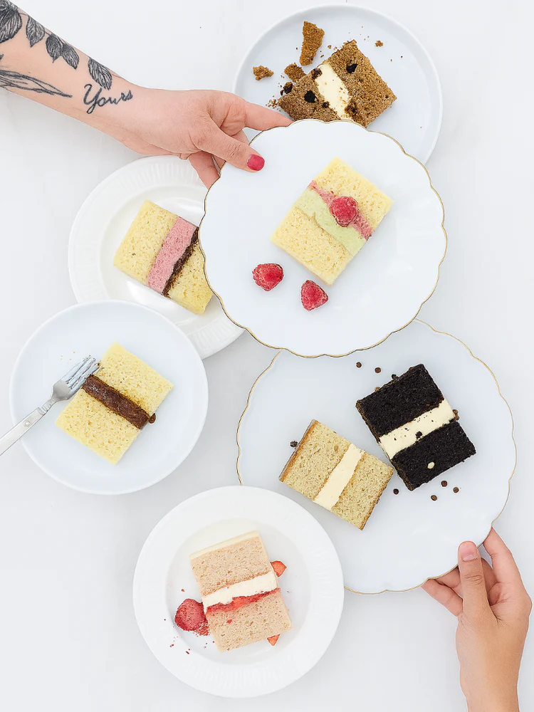Overhead flat lay of five layered cake slices in various flavors including chocolate, vanilla, and strawberry