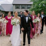 Joyful newlyweds with bridesmaids in pink gowns and groomsmen in tuxedos at outdoor wedding celebration