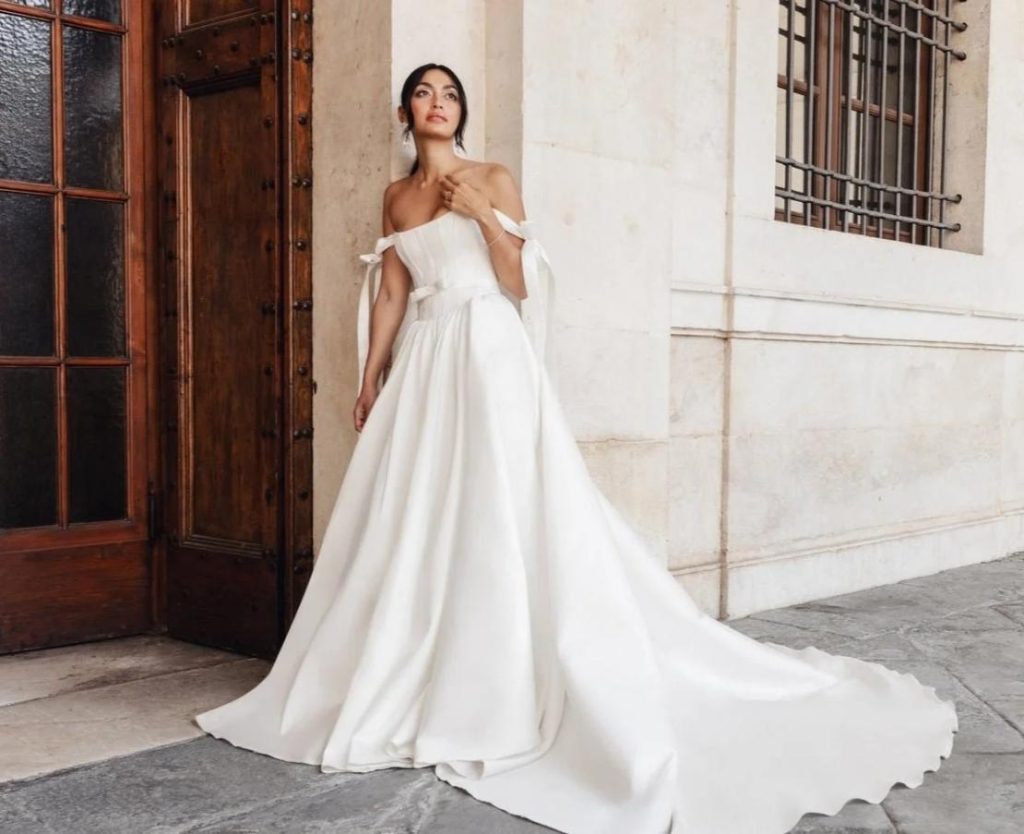 Bride in classic off-shoulder A-line wedding dress with ribbon-tied sleeves and dramatic train