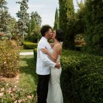 Bride and groom share romantic kiss among manicured gardens and flowering roses