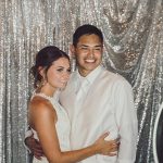 Bride and groom posing in photo booth with silver sequin backdrop