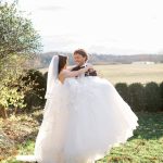 Bride and groom embrace on lawn overlooking rolling Virginia countryside in autumn