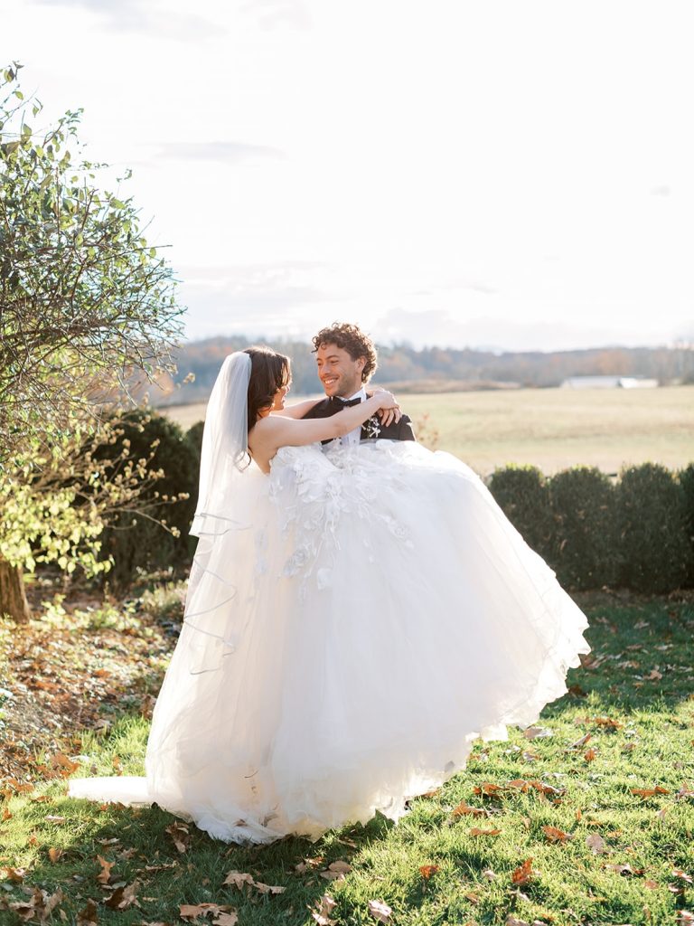 Bride and groom embrace on lawn overlooking rolling Virginia countryside in autumn