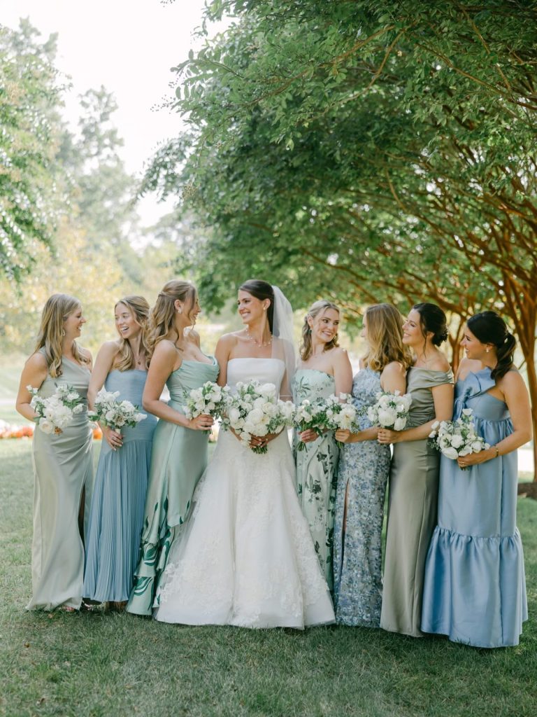 Bride and bridesmaids laughing together under tree in garden setting at Salamander Resort