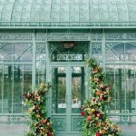 Victorian glass greenhouse entrance decorated with festive Christmas topiaries flanking the doorway