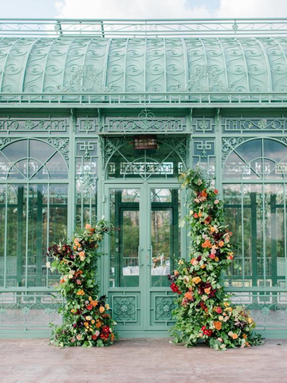 Victorian glass greenhouse entrance decorated with festive Christmas topiaries flanking the doorway