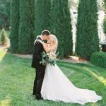 Bride and groom share intimate moment in garden with row of cypress trees