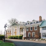 Grand brick Colonial-style mansion with white columns and green metal roof
