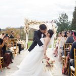 Bride and groom kissing at outdoor Virginia wedding ceremony with guests seated along stone aisle