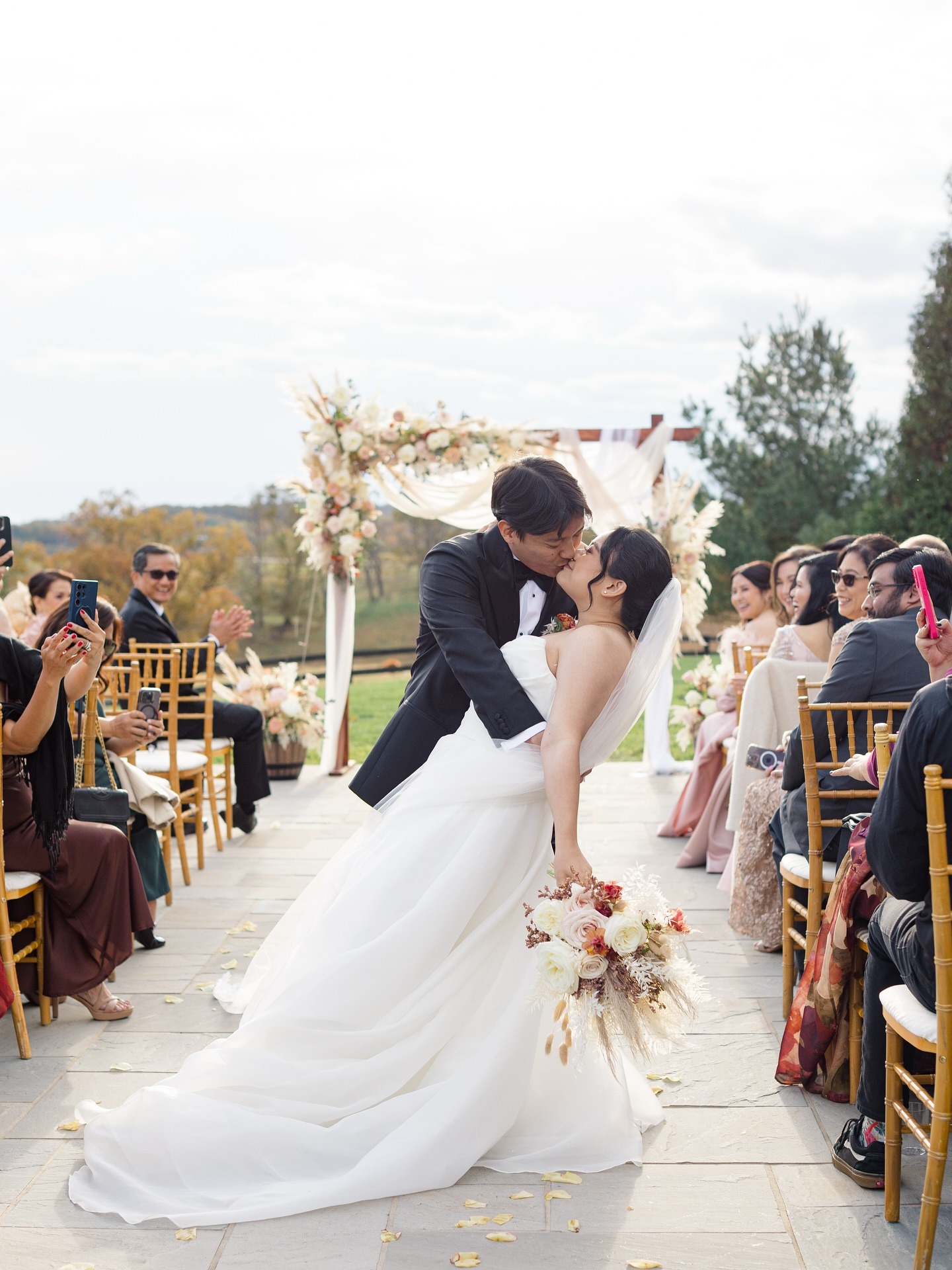 Bride and groom kissing at outdoor Virginia wedding ceremony with guests seated along stone aisle