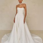 Modern bridal jumpsuit with strapless corset bodice, wide-leg pants, sheer choker detail, and dramatic cathedral train