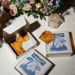 O'Malley's St. Louis style pizza boxes arranged beneath colorful floral centerpiece with crystal glassware