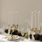 Elegant wedding table setting with brass candelabras, white tapers, crystal glassware, and fresh fruit centerpieces