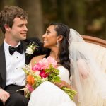 Bride with cascading waves and chandelier earrings smiling at groom on elegant outdoor settee