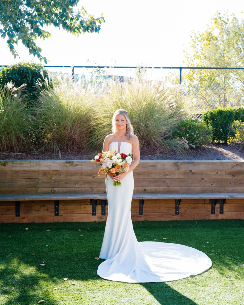 Bride in strapless mermaid gown holding colorful autumn bouquet outdoors