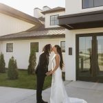 Newlyweds kissing outside modern white and black farmhouse-style Nebraska wedding venue