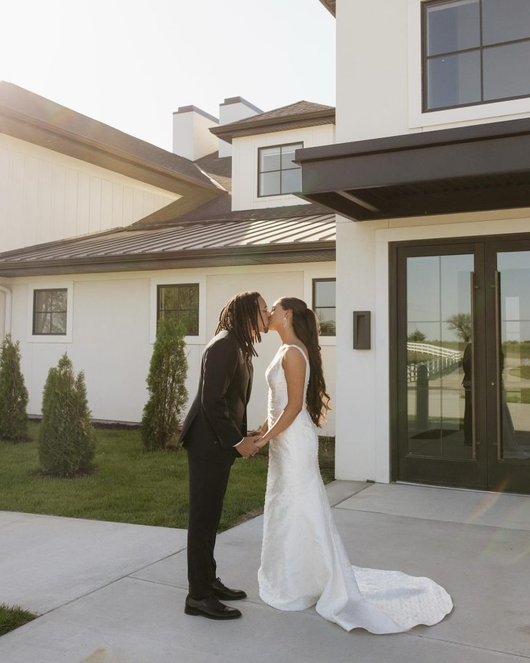 Newlyweds kissing outside modern white and black farmhouse-style Nebraska wedding venue