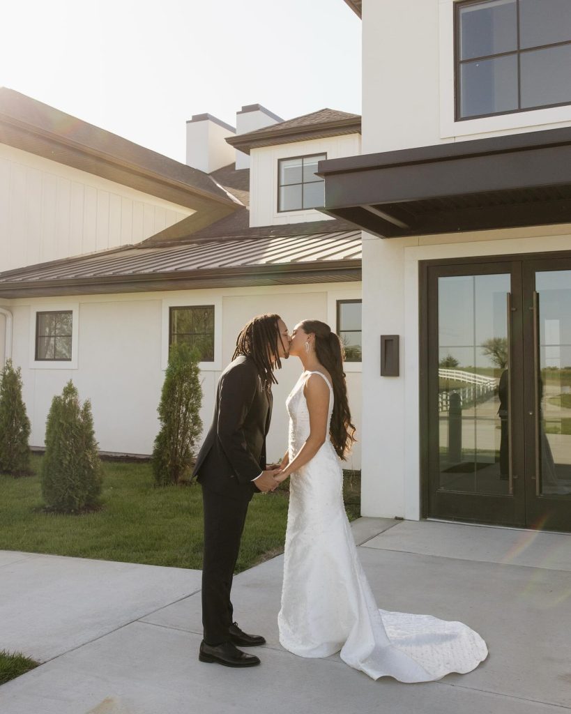 Newlyweds kissing outside modern white and black farmhouse-style Nebraska wedding venue
