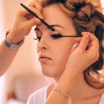 Makeup artist applying eyeliner to bride during wedding beauty preparation