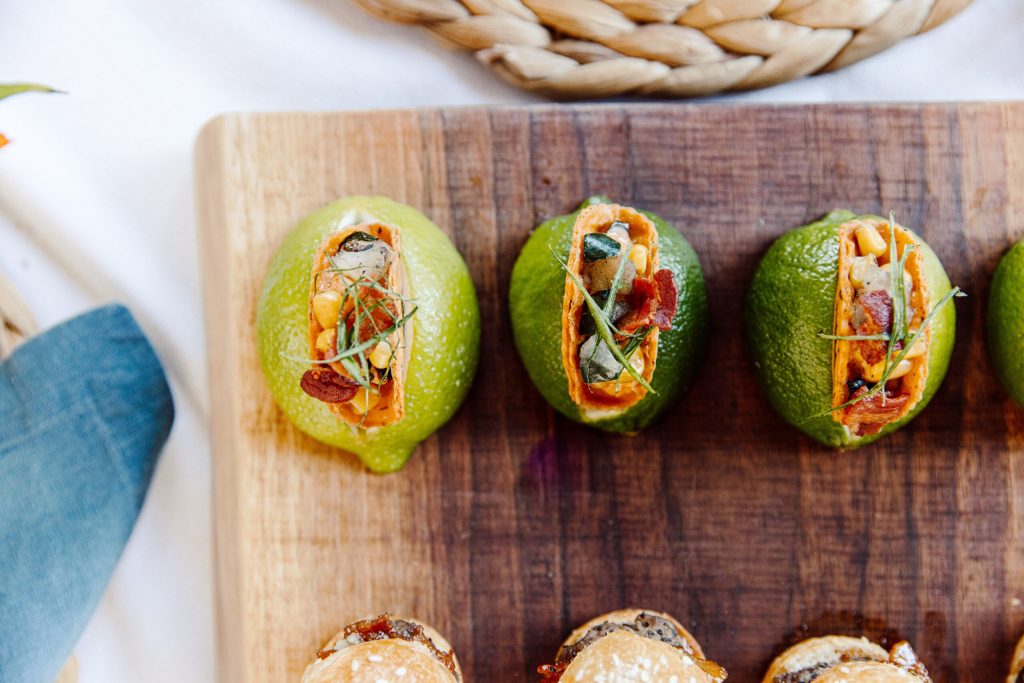 Stuffed avocado halves with vegetables and microgreens on wooden cutting board