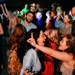 Joyful wedding guests dancing together at outdoor evening celebration