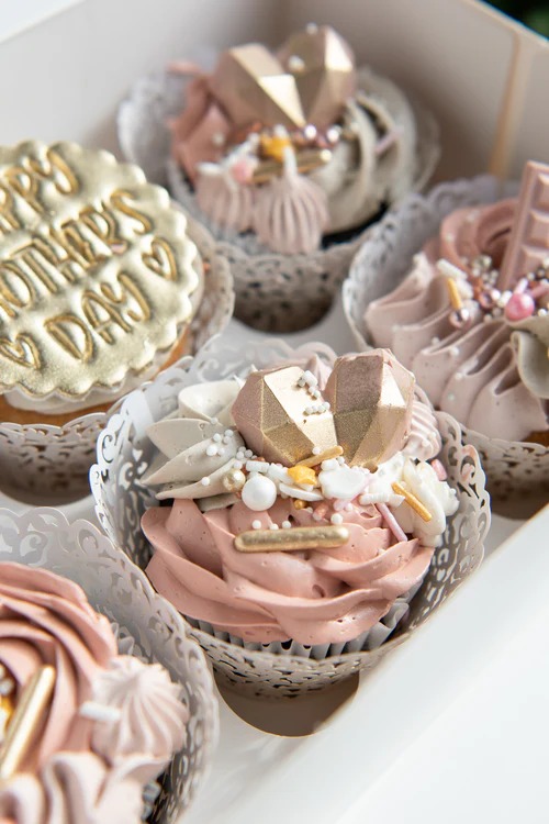 Decorated cupcakes with pink and white frosting, gold lettering, and pearl sprinkles