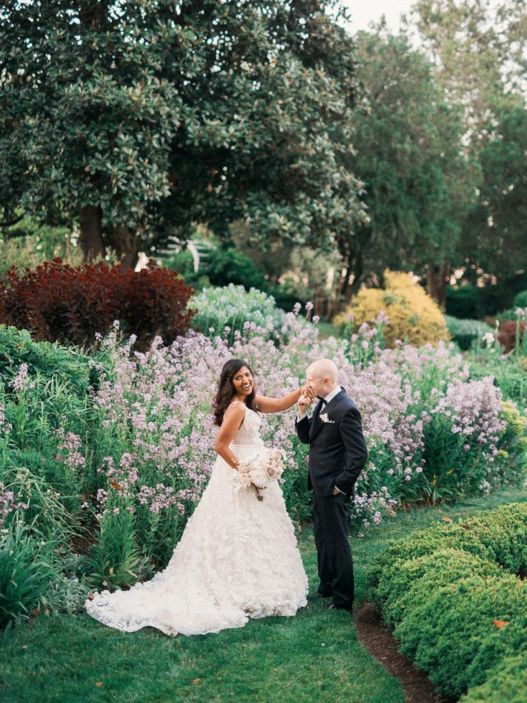 Bride and groom sharing an intimate moment in a lush garden with blooming lavender flowers and colorful shrubs