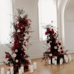 Dramatic floral installations with red and white roses flanking arched windows, surrounded by pillar candles