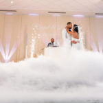 Bride and groom first dance surrounded by dramatic fog effect with DJ and sparkler fountains