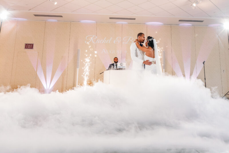 Bride and groom first dance surrounded by dramatic fog effect with DJ and sparkler fountains