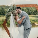 First kiss at waterfront wedding ceremony