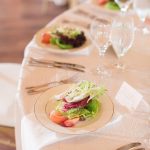 Gold-rimmed plates with artfully arranged salads featuring fresh greens, grapefruit, and microgreens at formal wedding reception