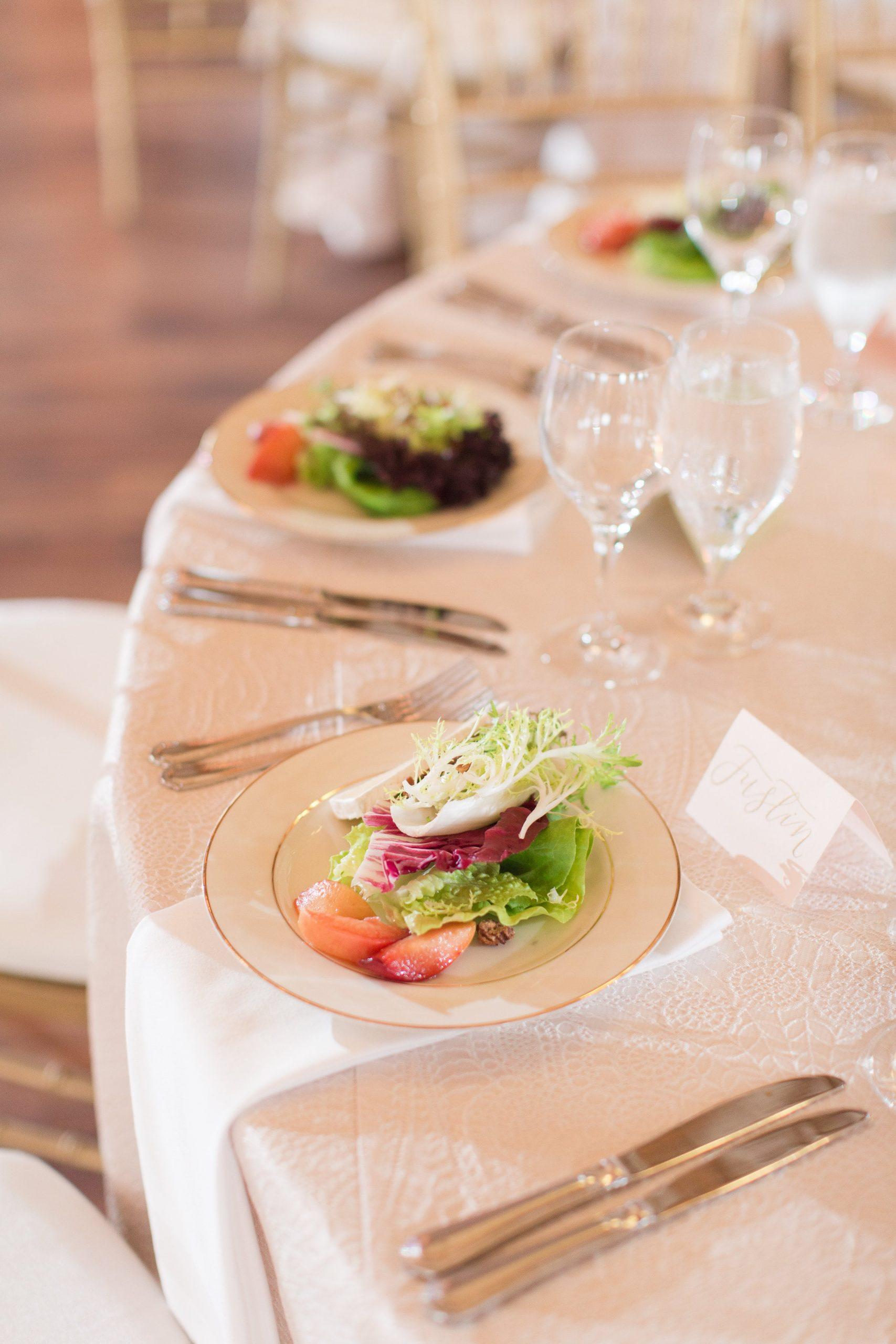 Gold-rimmed plates with artfully arranged salads featuring fresh greens, grapefruit, and microgreens at formal wedding reception
