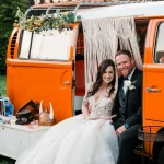 Bride and groom in vintage orange Volkswagen bus photo booth