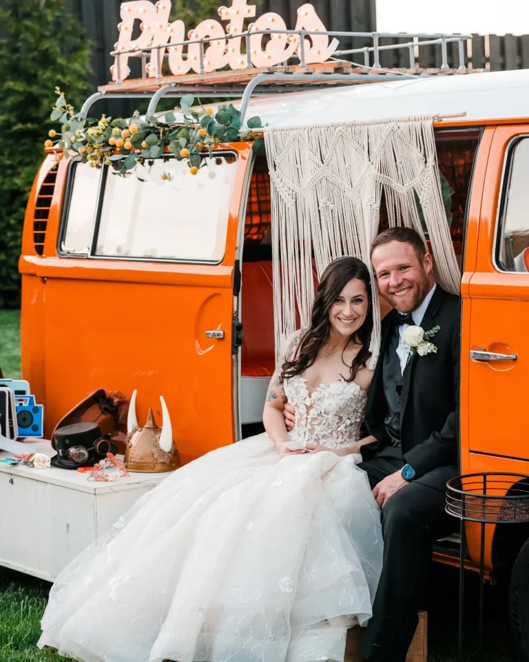 Bride and groom in vintage orange Volkswagen bus photo booth